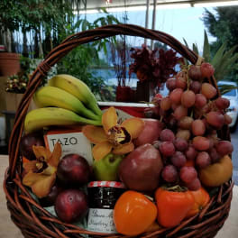 Fruit basket with grapes, bananas, citrus, and orchids in a wicker basket