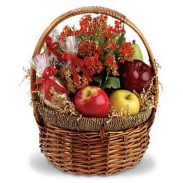 Gift basket with red flowers, apples, and wrapped nuts in a wicker basket