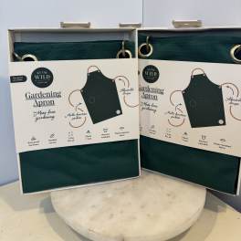 Two boxed green gardening aprons on a table