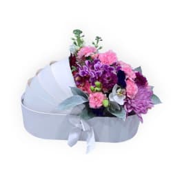 Mixed pink and purple bouquet in a white heart-shaped box with ribbon