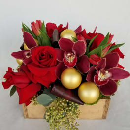 Red roses and burgundy orchids arranged in a box with gold ornaments