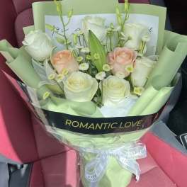 Bouquet of white and blush roses wrapped in pale green paper