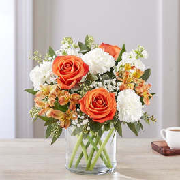 Orange roses and white carnations in a clear glass vase