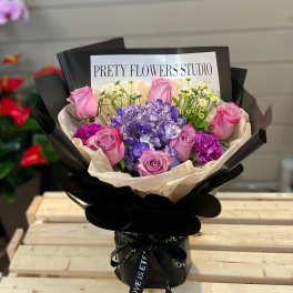 Bouquet of pink roses and purple hydrangea in black wrapping