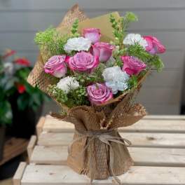 Pink and white roses arranged in brown paper wrapping