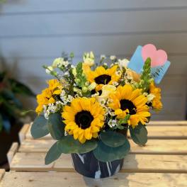 Sunflower bouquet in a dark vase with a pink heart pick