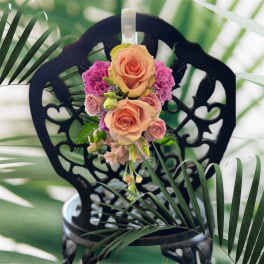 Peach and pink rose bouquet with purple carnations on a black decorative chair
