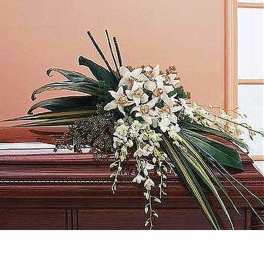 Elongated white lily and orchid casket spray with cascading blooms and large green leaves