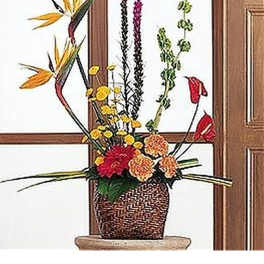 Tall tropical floral arrangement with birds of paradise and bright mixed flowers in a woven basket