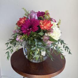 Mixed bouquet of pink, white, and coral flowers in a glass vase