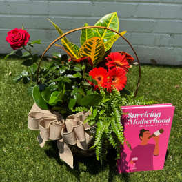 Basket arrangement with a red rose, orange gerberas, and a pink card