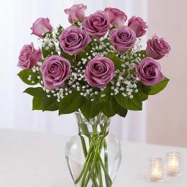 Lavender roses arranged in a clear glass vase with baby's breath