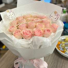 Bouquet of pale pink roses wrapped in white paper with Hello Kitty toppers