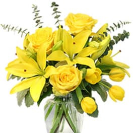 Yellow roses and lilies arranged in a clear glass vase
