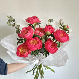Bouquet of bright pink peonies wrapped in white paper
