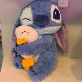 Blue plush character holding a small white duck plush