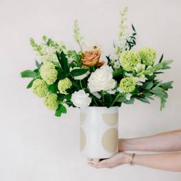 Bouquet of white and peach roses with green blooms in a patterned vase