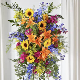 Tall standing arrangement with sunflowers, lilies, and blue flowers