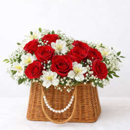 Red roses and white flowers in a wicker basket with pearl handles