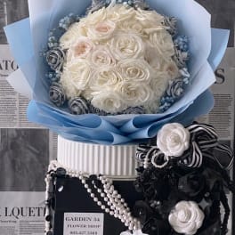 White rose bouquet wrapped in pale blue paper with black-and-white ribbon accents