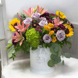 Mixed bouquet in a white hat box with sunflowers, lilies, and lavender roses