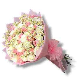 Bouquet of pink and white roses with small white daisies in pink wrap