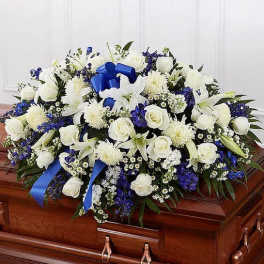 White and blue floral spray on a wooden casket