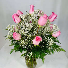 Pink roses arranged with white baby's breath in a glass vase
