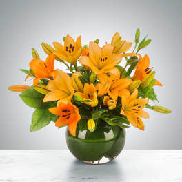 Orange lilies arranged in a green glass vase