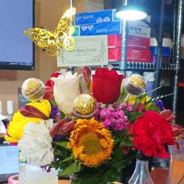 Mixed bouquet in a glass vase with roses, carnations, and a sunflower