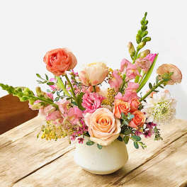Pastel flower arrangement in a white vase on a wooden table