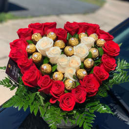 Heart-shaped bouquet of red and white roses with gold-wrapped chocolates