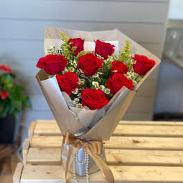 Bouquet of red roses with small white daisies in beige wrapping