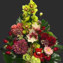 Mixed flower basket with orchids, roses, hydrangeas, and a small teddy bear