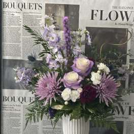 Lavender and white bouquet in a white vase with ribbon and pearl accents