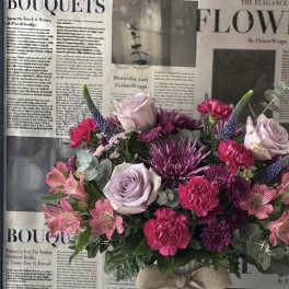 Bouquet of pink, lavender, and purple flowers in a white vase with a bow