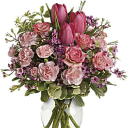Pink tulips and roses arranged in a clear glass vase