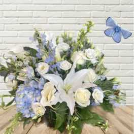 White lilies, roses, and blue flowers in a low arrangement with a butterfly accent
