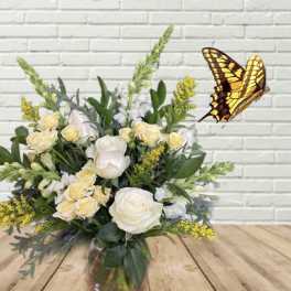 White and pale yellow flower arrangement with a butterfly decoration