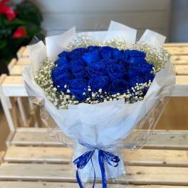 Bouquet of vivid blue roses with white baby's breath in white wrapping