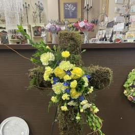 Moss-covered cross arrangement with yellow and white flowers