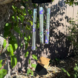 Hanging black wind chime with floral tubes and a tag