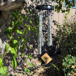 Hanging silver wind chime on a tree branch outdoors
