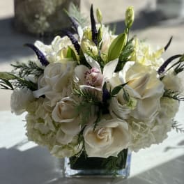 White rose and orchid bouquet in a square glass vase
