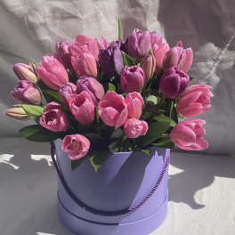 Pink and purple tulips arranged in a lavender round box