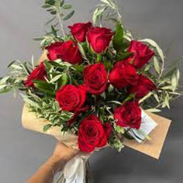 Bouquet of red roses with variegated greenery wrapped in paper