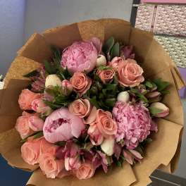Pink bouquet of roses and peonies wrapped in brown paper