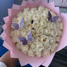 Bouquet of cream roses wrapped in pink paper with purple butterfly picks