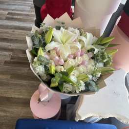 Bouquet of white lilies and pale pink roses wrapped in paper