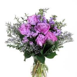 Purple roses and lavender flowers in a clear glass vase